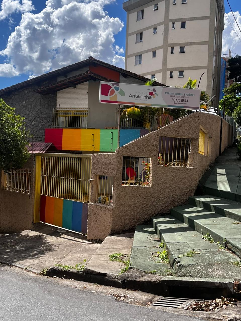 Fachada da Escola Anteninha com placa de identificação, portão e muro coloridos